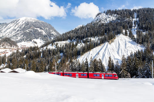 Winterlandschaft im Schanfigg mit einem Zug der Arosabahn zwischen Langwies und Litzirüti, Kanton Graubünden.