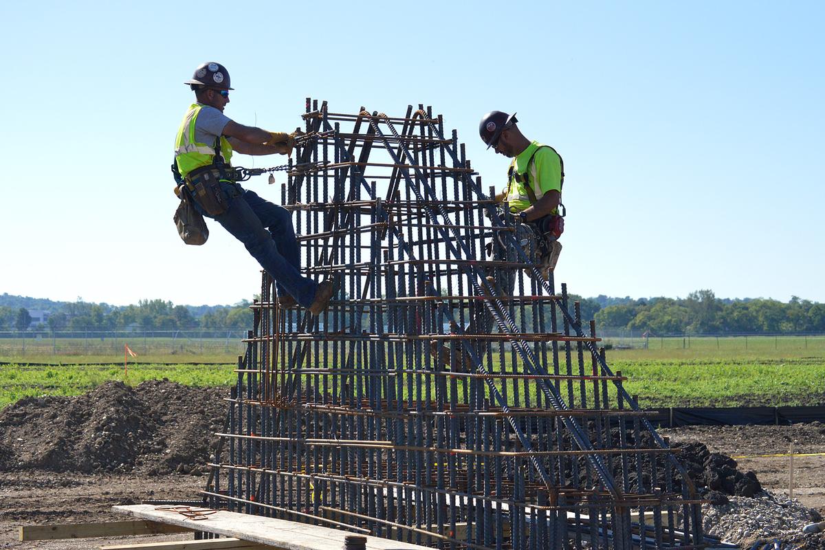 Construction crews tie together the steel rebar for an arch springing 