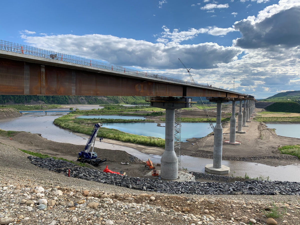 Le Halfway River Bridge en construction, mai 2021. Les piles coniques signalent le futur plan d'eau du barrage