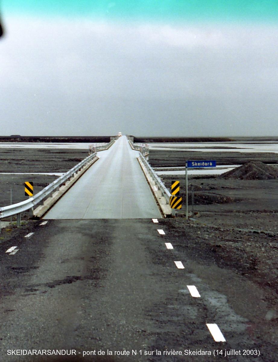 Fiche média no. 46017 SKEIDARARSANDUR (désert de sable entre le glacier Vatnajökull et le mer, région sud) – Pont de la rivière Skeidara, emporté (avec 10 km de la route n° 1) par la «crue glaciaire» du Vatnajökull, en novembre 1996 (la plus importante du siècle), il a été reconstruit sensiblement à l'identique: voie unique, poutres métalliques en I supportant le tablier