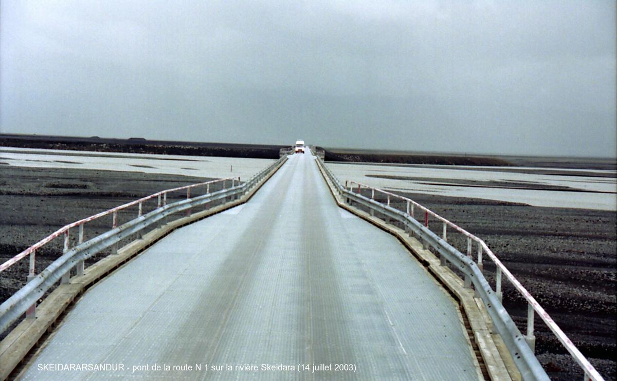 Fiche média no. 46018 SKEIDARARSANDUR (désert de sable entre le glacier Vatnajökull et le mer, région sud) – Pont de la rivière Skeidara, emporté (avec 10 km de la route n° 1) par la «crue glaciaire» du Vatnajökull, en novembre 1996 (la plus importante du siècle), il a été reconstruit sensiblement à l'identique: voie unique, poutres métalliques en I supportant le tablier