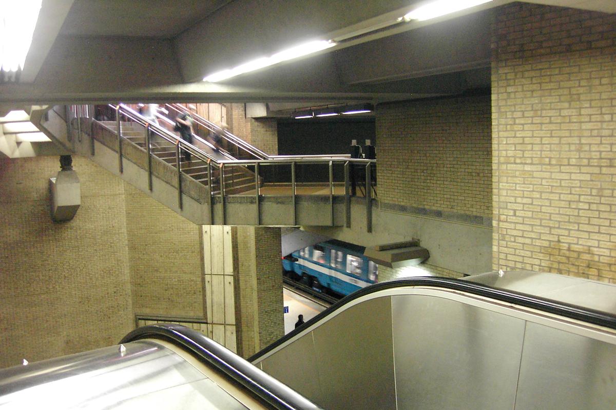 Fiche média no. 90333 Station de Castelnau; Au centre de la photo, escalier partant en haut de l'édicule et qui accède au niveau mezzanine. en bas de l'escalier mécanique, un train direction Saint-Michel laissant descendre et entrer des passagers. 05/12 Ligne Bleue Métro de Montréal