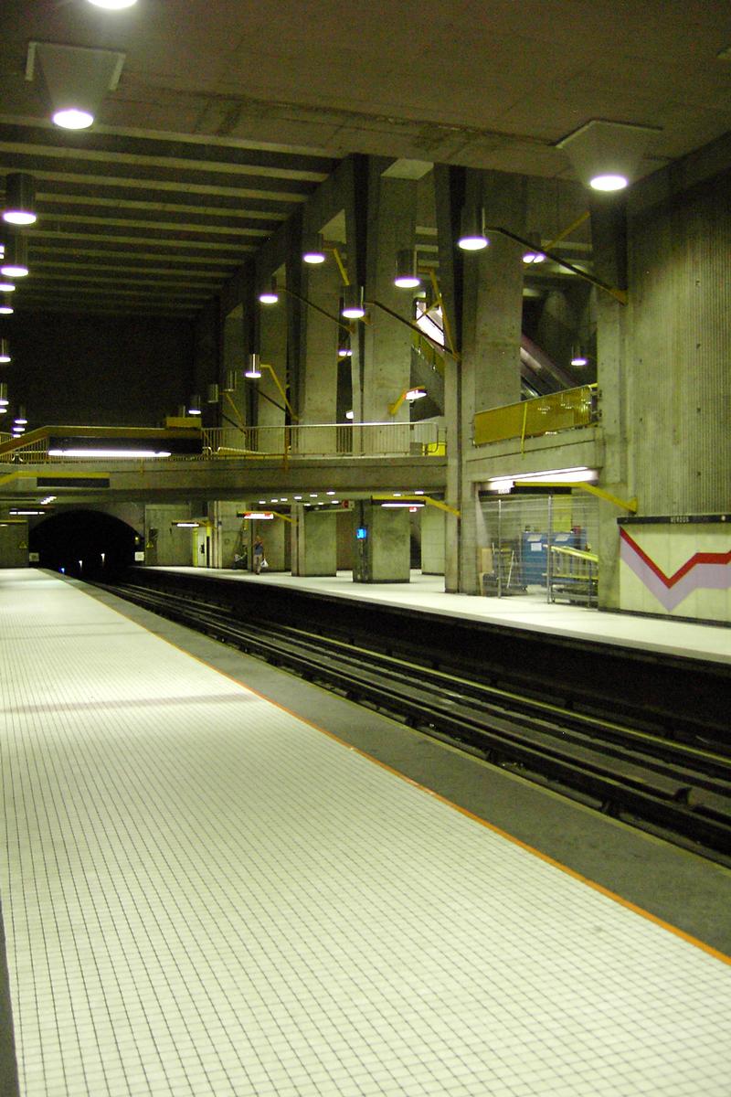 Fiche média no. 89426 Station Verdun, à mi chemin entre les deux extrémités de la station; en regardant en direction Honoré-Beaugrand, remarquez en haut à droite derrière les colonnes de béton, les escaliers mécaniques menant en surface. 24/27 ligne verte Métro de Montréal
