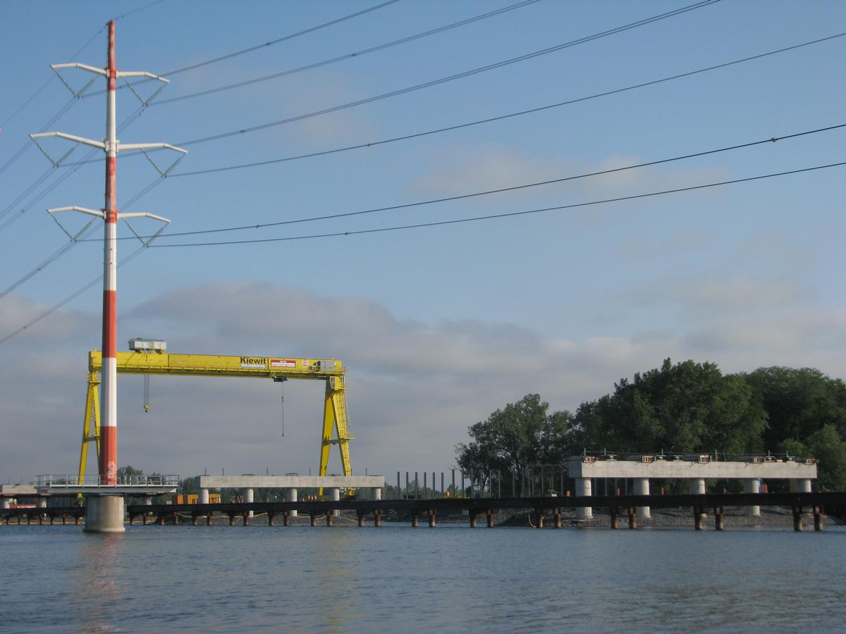 Fiche média no. 145418 Piliers à chevêtre complétés et pont portique(en jaune) servant à poser les sections de poutres en acier de quatre mètres de hauteur au dessus de la rivière
