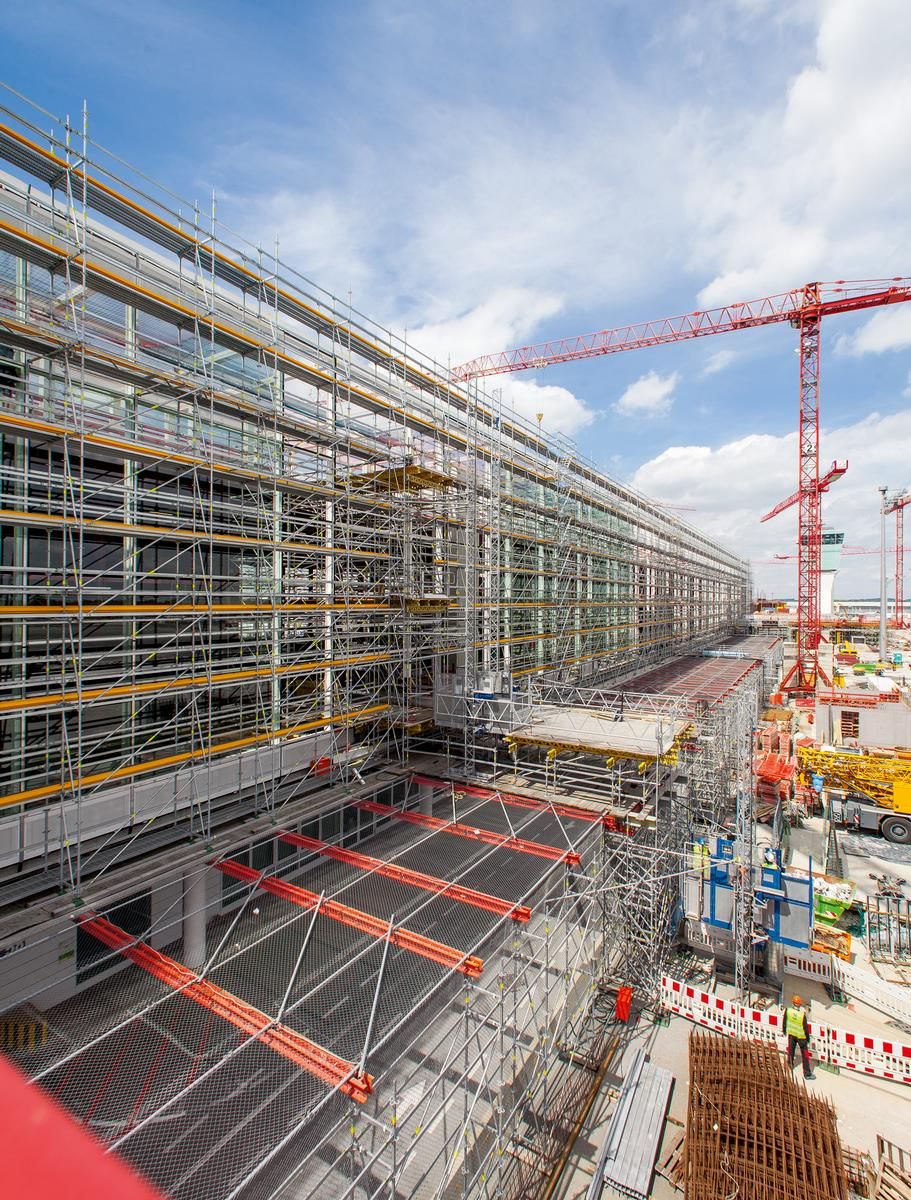 Media File No. 225983 The PERI UP scaffolding construction reliably shields construction site activities from airport operations. At the same time, it serves as working scaffold for the facade contractors. Stair access and large-span bridging enhance the scaffold solution of the Weissenhorn experts.