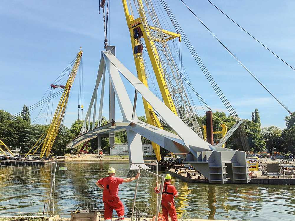 The two prefabricated main elements of the steel bridge were positioned using three floating cranes. The two prefabricated main elements of the steel bridge were positioned using three floating cranes.