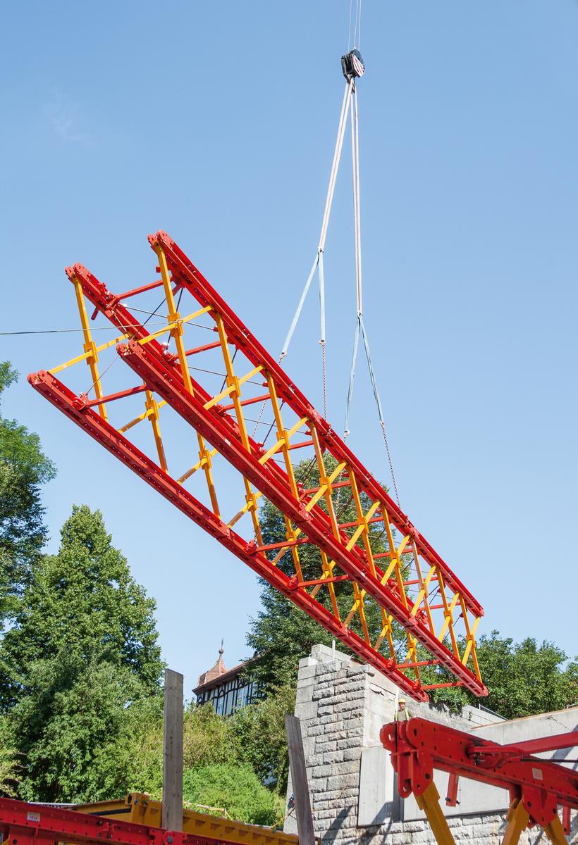 Media File No. 243149 Modular shoring assembly: VARIOKIT system components were pre-assembled on the ground to form truss segments and placed into intermediate storage with the crane. Three such segments were subsequently coupled to create a 37 m long truss unit and lifted over the Mur by means of a mobile crane.