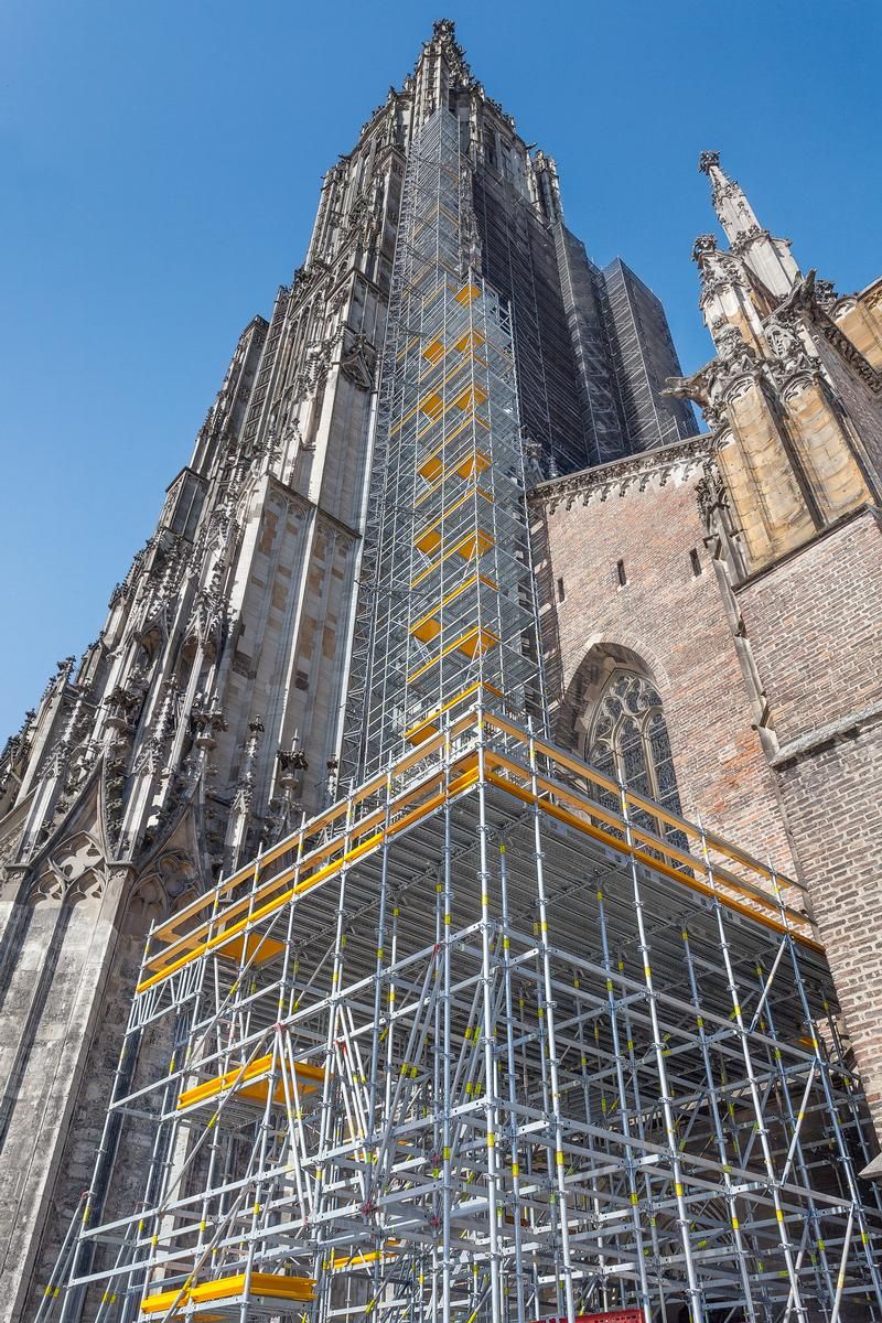 Mediendatei Nr. 251002 PERI UP schmiegt sich für die umfangreichen Sanierungsarbeiten bis auf 71 m Höhe an das Ulmer Münster, eine Zwischenplattform in 7 m Höhe dient als Lagermöglichkeit für die neuen Steine.