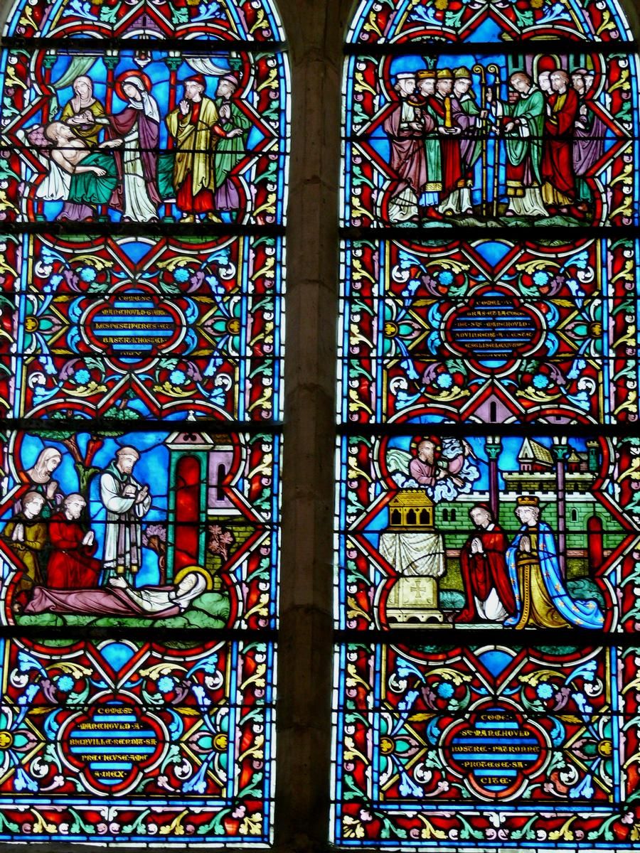 Sainte-Ménehould - Eglise Notre-Dame-du-Château Chapelle de Sainte-Ménehould - Vitrail de droite racontant la vie de sainte Ménéhould, fille cadette du comte Sygmar et de son épouse Lintrude: ; à gauche, en haut: comment sainte Ménehould a bâti pour les pestifrés de l'hospice,; à gauche en bas: mort de sainte Ménehould à Bienville le 14 octobre 490 (ou 500),; à droite en haut: en 1378, Jehan de Saulx et quelques bourgeois ramènent de reliques de la sainte à Sainte-Ménehould,; droite en bas: comment sainte Ménehould, patronne de la ville, protège sa cité.