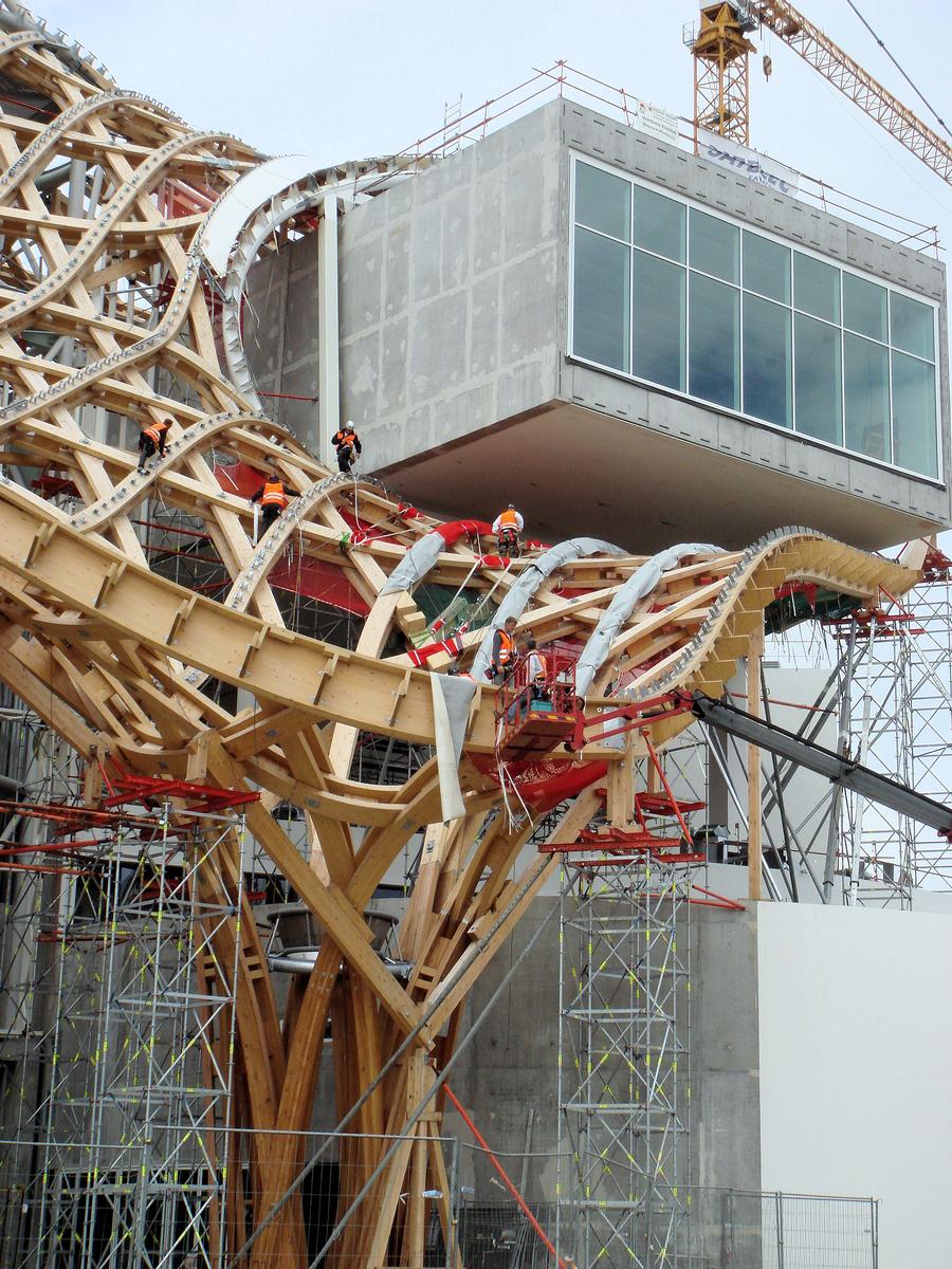 Metz - Centre Pompidou Metz - Montage de la charpente bois sur échafaudage - Début du montage de la toile au-dessus du tube le plus haut 