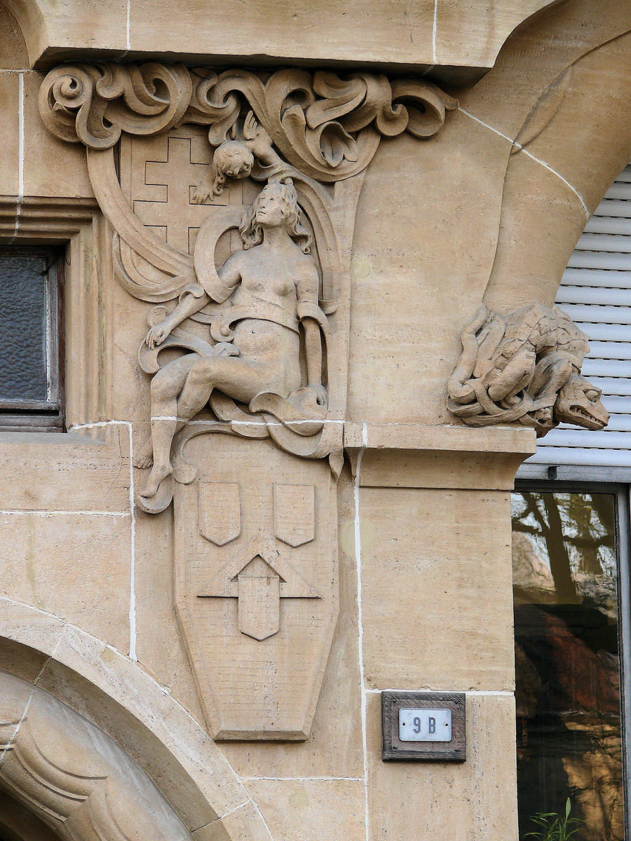 Fiche média no. 134679 Metz - Immeuble 9 avenue Foch - Détail: une représentation lascive de la Lothringer Baugesellschaft assice sur les emblèmes du constructeur et se tournant vrs une croix de Lorraine. Dragon gardant la fenêtre