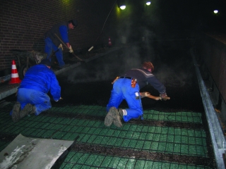Verlegen der Gussasphaltdeckschicht auf einer Rampe mit elektrischer Rampenheizung bei Nacht 