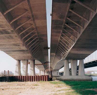 Bottom view of bridge featuring piers and both traffic lanes 