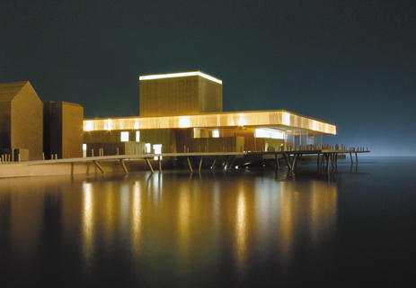 Media File No. 51983 The building, with a front facade made of copper and glass, cantilevers in part over the harbour basin and is supported on reinforced concrete piles over the surface of the water