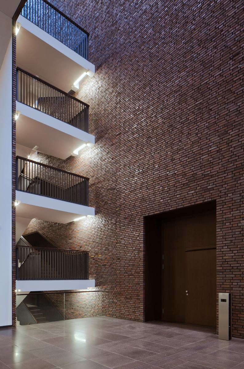 In der schmaleren Fuge stellen abgesetzte Treppenläufe die verklinkerten Wände frei. Die Linearleuchten betonen diesen Aspekt 