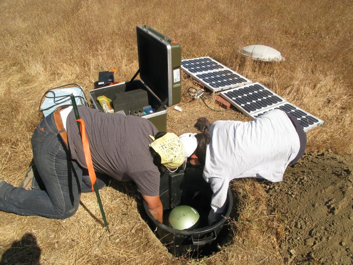 Mediendatei Nr. 217775 Endgültige Messposition: Kayla Kroll und Tien Huei-Wang (University of California, Riverside) heben das KIT Seismometer STS-2 in eine Kammer im Boden, der Boden wurde zuvor zementiert