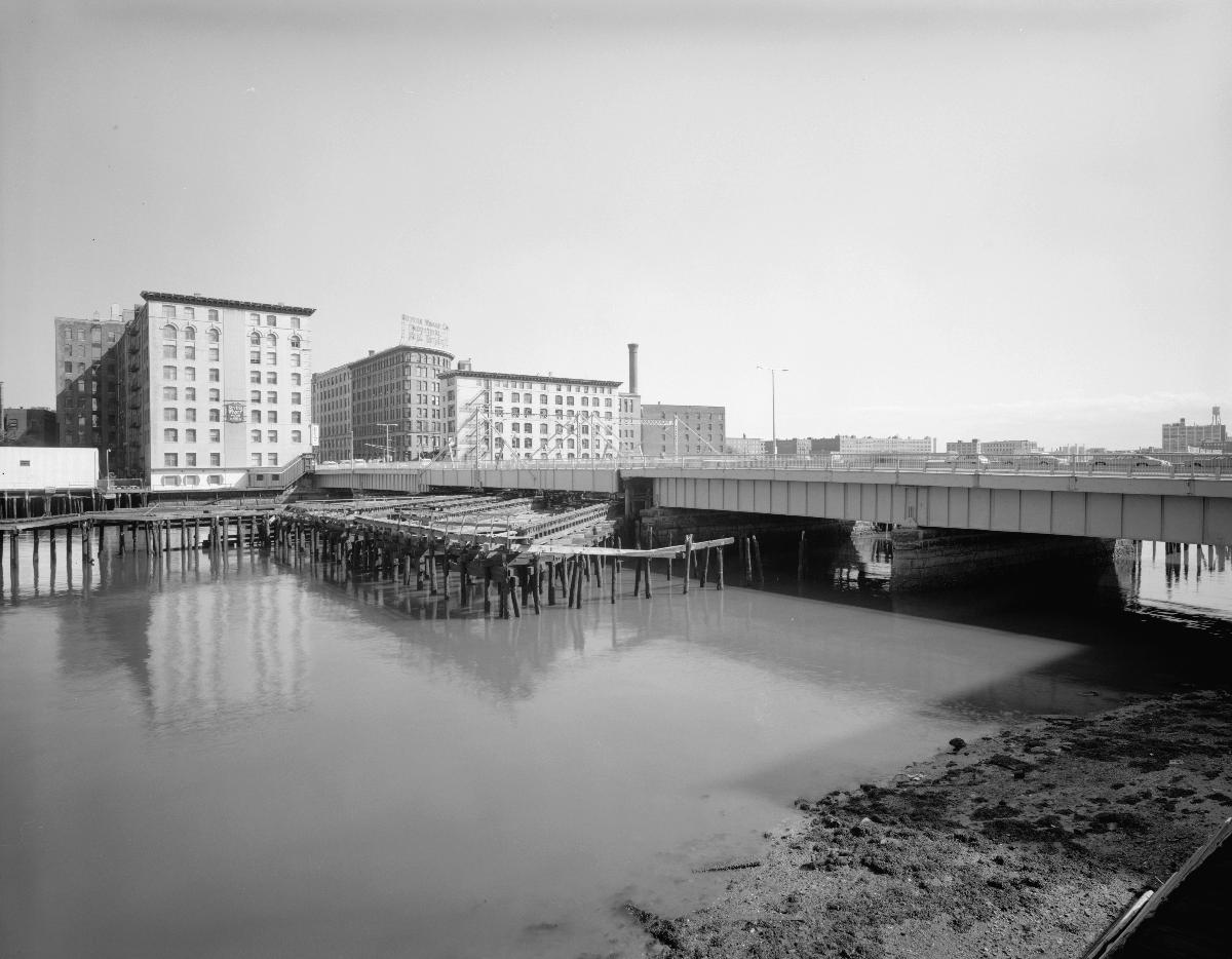 Media File No. 199242 SUMMER STREET BRIDGE. DRAW SPAN MOVES TOWARD VIEWER ON TRACKS VISIBLE AT CENTER OF PHOTOGRAPH. - Summer Street Retractile Bridge, Spanning Fort Point Channel at Summer Street, Boston, Suffolk County, MA (HAER MASS,13-BOST,87–1)