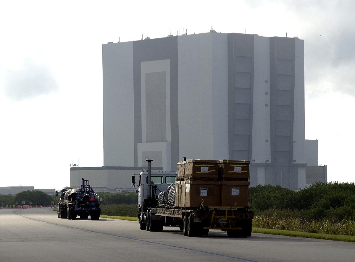 Vehicle Assembly Building (VAB) Flatbed trucks carrying some of the debris of Space Shuttle Columbia approach the Vehicle Assembly Building (VAB). The debris is being transferred from the Columbia Debris Hangar to the VAB for permanent storage. More than 83,000 pieces of debris were shipped to KSC during search and recovery efforts in East Texas. That represents about 38 percent of the dry weight of Columbia, equaling almost 85,000 pounds.