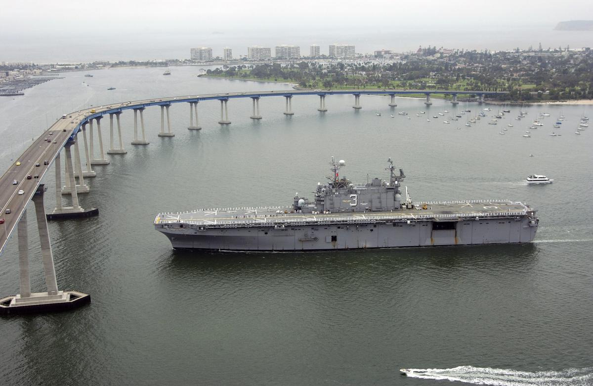 San Diego-Coronado Bay Bridge Aerial port side view of the US Navy (USN) Tarawa Class Amphibious Assault Ship USS BELLEAU WOOD (LHA 3), showing Sailors manning the rails as the ships approaches the Coronado Bridge for the final time while completing her final voyage after 27 years of service