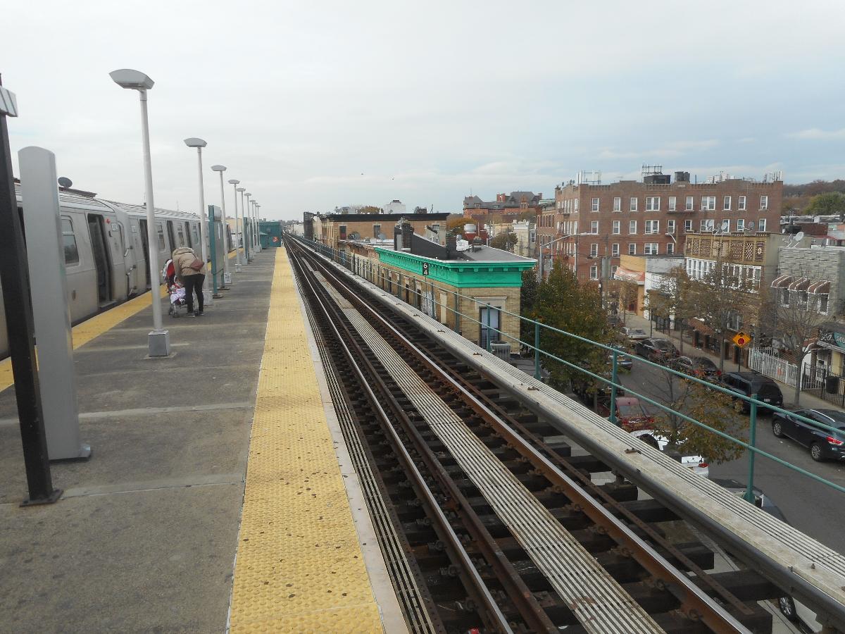 Norwood Avenue Station Looking west along the center of the platform of the Norwood Avenue Elevated Railway station on the BMT Jamaica Line in the Cypress Hills section of Brooklyn, New York City, while a Jamaica-bound train discharges passengers. Along side that building with the green roof trim, is Arlington Avenue as seen from above Hale Avenue.