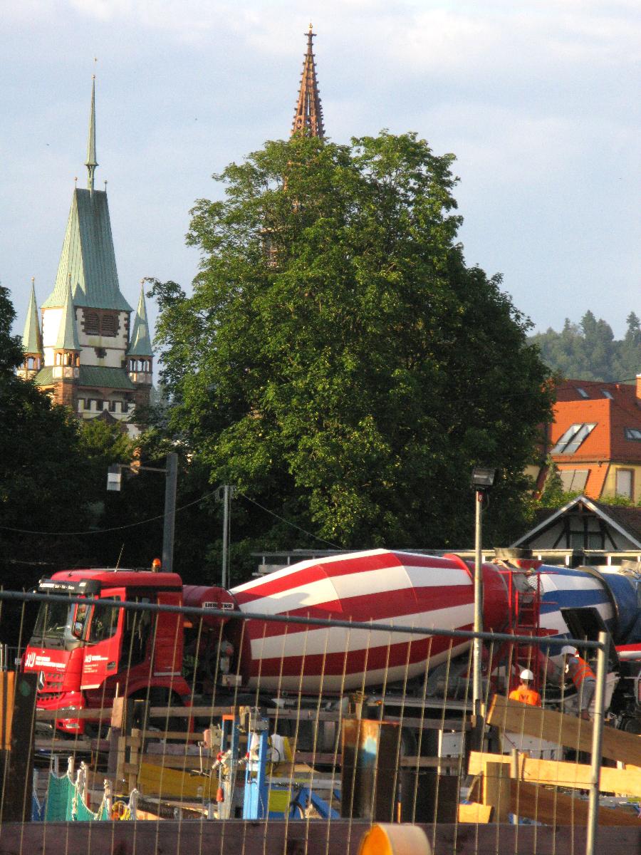 Betonierung der Freiburger Kronenbrücke, Fahrmischer mit Martinstor und Münsterturm im Hintergrund 