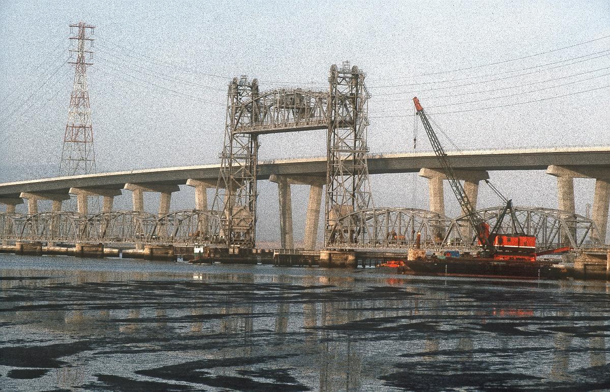 Dumbarton Bridges The original vertical-lift Dumbarton Bridge is shown alongside its replacement span, shortly before the demolition of the older bridge in September 1984. The bridge is the southernmost crossing of the San Francisco Bay.