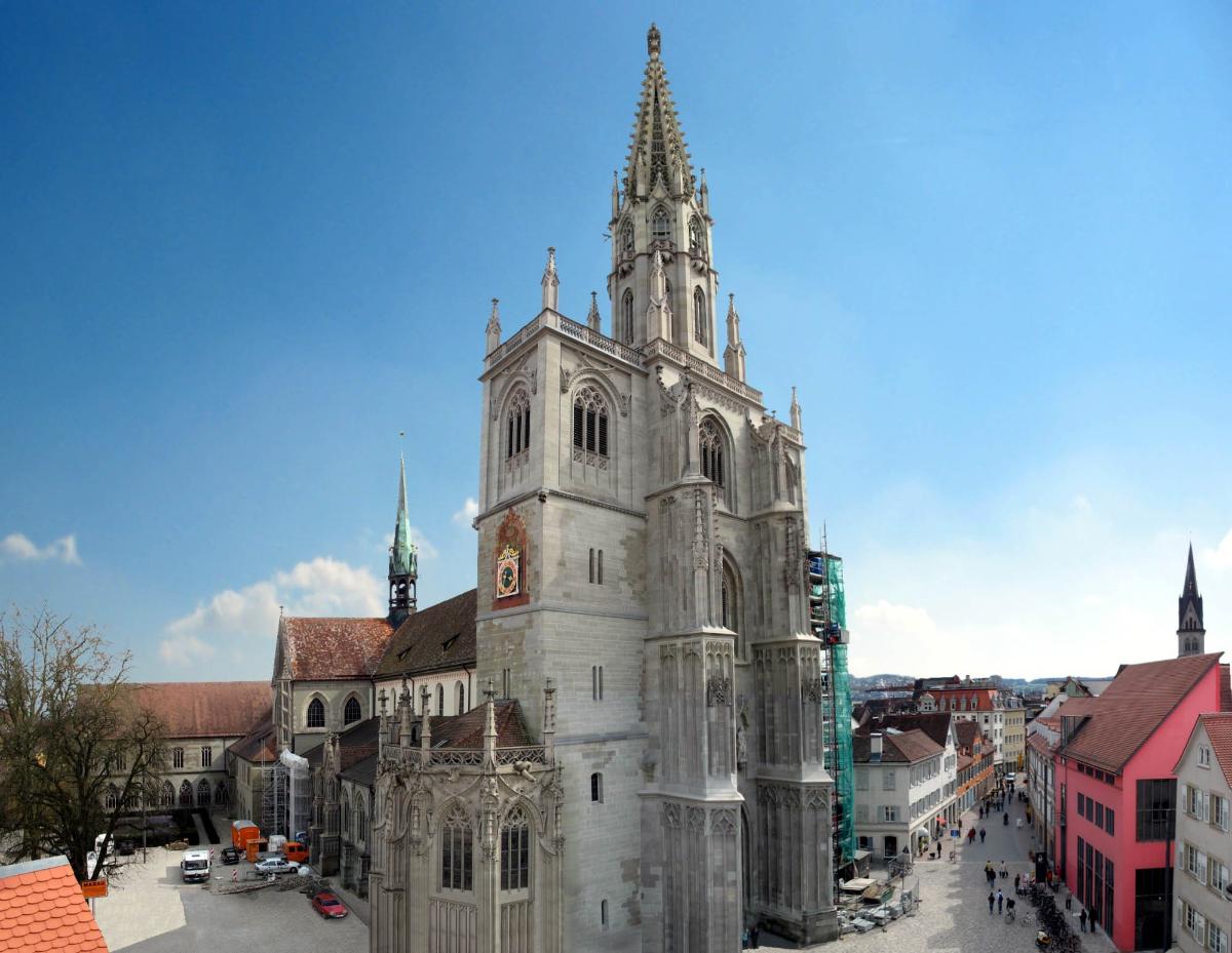 Cathédrale Notre-Dame de Constance et ses environs, vus du nord-ouest Assemblage de plusieurs photographies. On distingue, de gauche à droite: le cloître (au second plan, à gauche)
; le bras septentrional du transept, avec flèche de croisée
; la chapelle Welser (tout à l'avant-plan)
; les clochers nord et sud (au milieu de la photo, avec échafaudages)
; la place de la Cathédrale (Münsterplatz), à gauche, et la rue Wessenberggasse, à droite
; la façade rouge du centre culturel 'am Münsterplatz' 
; le clocher de l'église Saint-Étienne (St. Stephan, à l'arrière-plan à droite, contre le bord droit de la photo).