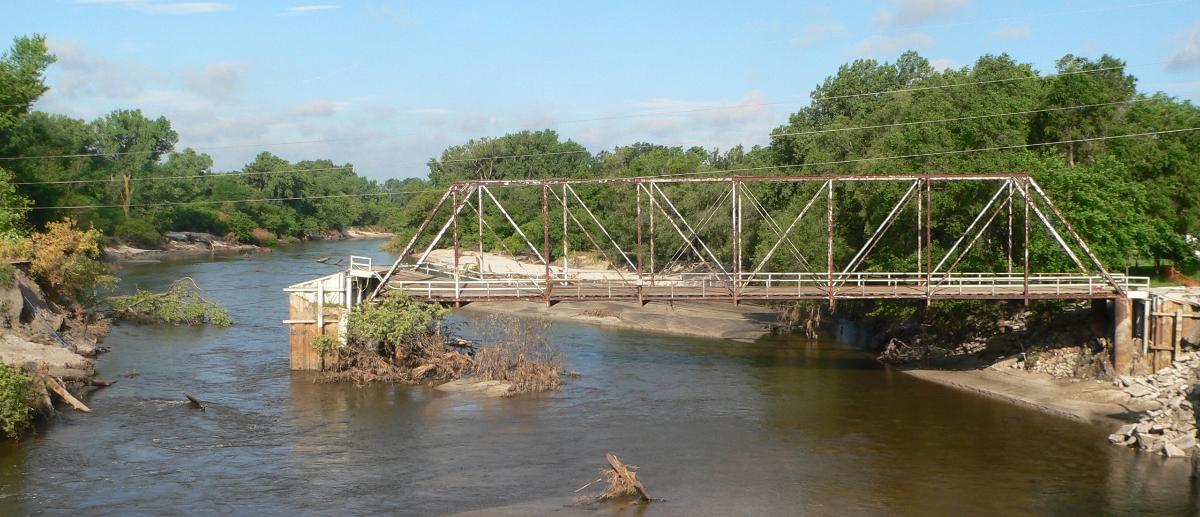 Neligh Mill Bridge Neligh Mill Bridge over the Elkhorn River in Neligh, Nebraska; seen from the east (downstream). The pin-connected Pratt through truss bridge was constructed in 1910; it is listed in the National Register of Historic Places. The photo was taken ca. 2 weeks after major flooding on the Elkhorn in June 2010; beside the erosion south of the south abutment, note the partial collapse of the deck at the south end.