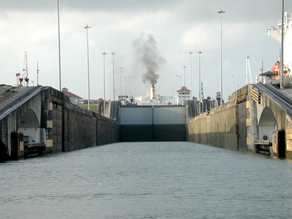 Media File No. 209477 One of the lock chambers in the Panama Canal. The view is from a small boat about to enter the east flight of the Gatun locks, heading south towards the Pacific side. A ship can be seen in the next chamber up; on either side of the lock are the railway tracks on which the mules run. Within the arches to either side in the foreground are the halves of a swinging road bridge
