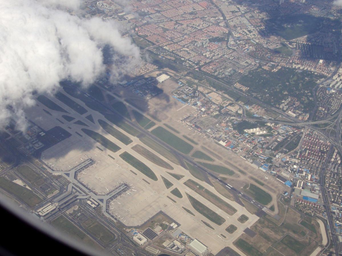 Aerial photo of Shanghai Hongqiao International Airport Looking from the southwest. The huge terminal 2 of the airport, and a small part of the adjacent Hongqiao Railway Station are near the bottom left corner of the image. The much smaller Terminal 1 is near the center.