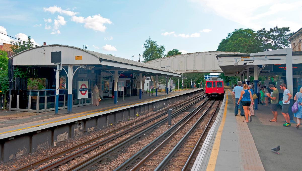 Looking south along the platform at Kew Gardens station in London as a District Line train arrives 