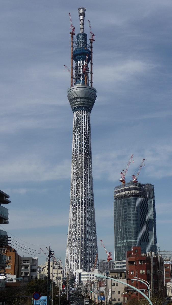 Media File No. 178113 Tokyo Sky Tree under construction at a height of 559 m. The tower tip tuned mass damper room, four 4-layer of digital terrestrial television (ISDB-T) antennas and craning mast of tower cranes are covered by net to prevent to drop off the lump of fallen and cumulated snow on pedestrian on the ground