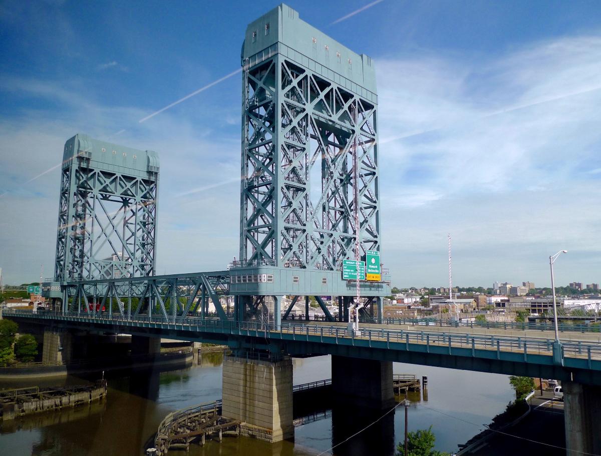 The William A. Stickel Memorial Bridge A 1949 vertical-lift bridge carrying I-280 across the Passaic River between Newark and East Newark, New Jersey, viewed from a train on the parallel Newark Drawbridge (or Morristown Line Bridge).