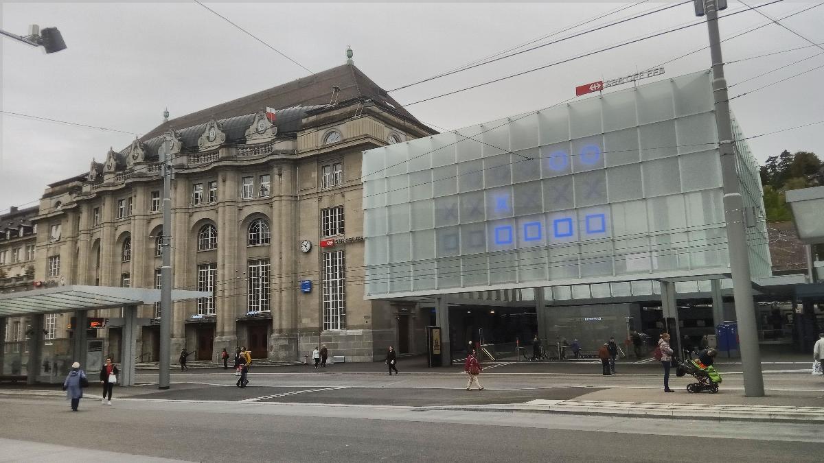 Blick von Südosten auf die Front und den neuen Hauptzugang des St. Galler Bahnhofs Rechts der Glaskubus mit der binären Uhr, links das alte Bahnhofgebäude.