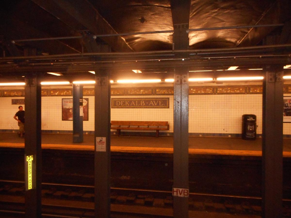 DeKalb Avenue Subway Station (Canarsie Line) West Village-bound platforms of DeKalb Avenue (BMT Canarsie Line), as seen from the Rockaway Parkway-bound platform. This contains the traditional mosaics that were originally added to BMT subway stations, which are right over a bench.