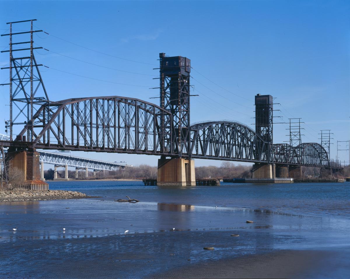 Die Delair Bridge über den Delaware bei Philadelphia, Pennsylvania, von Westen aus gesehen Auf dem Bild sind die insgesamt vier Öffnungen zu erkennen. Die zweite Öffnung mit den beiden Türmen ist die Hubbrücke, die dritte mit dem runden Pfeiler die alte Drehbrücke.
