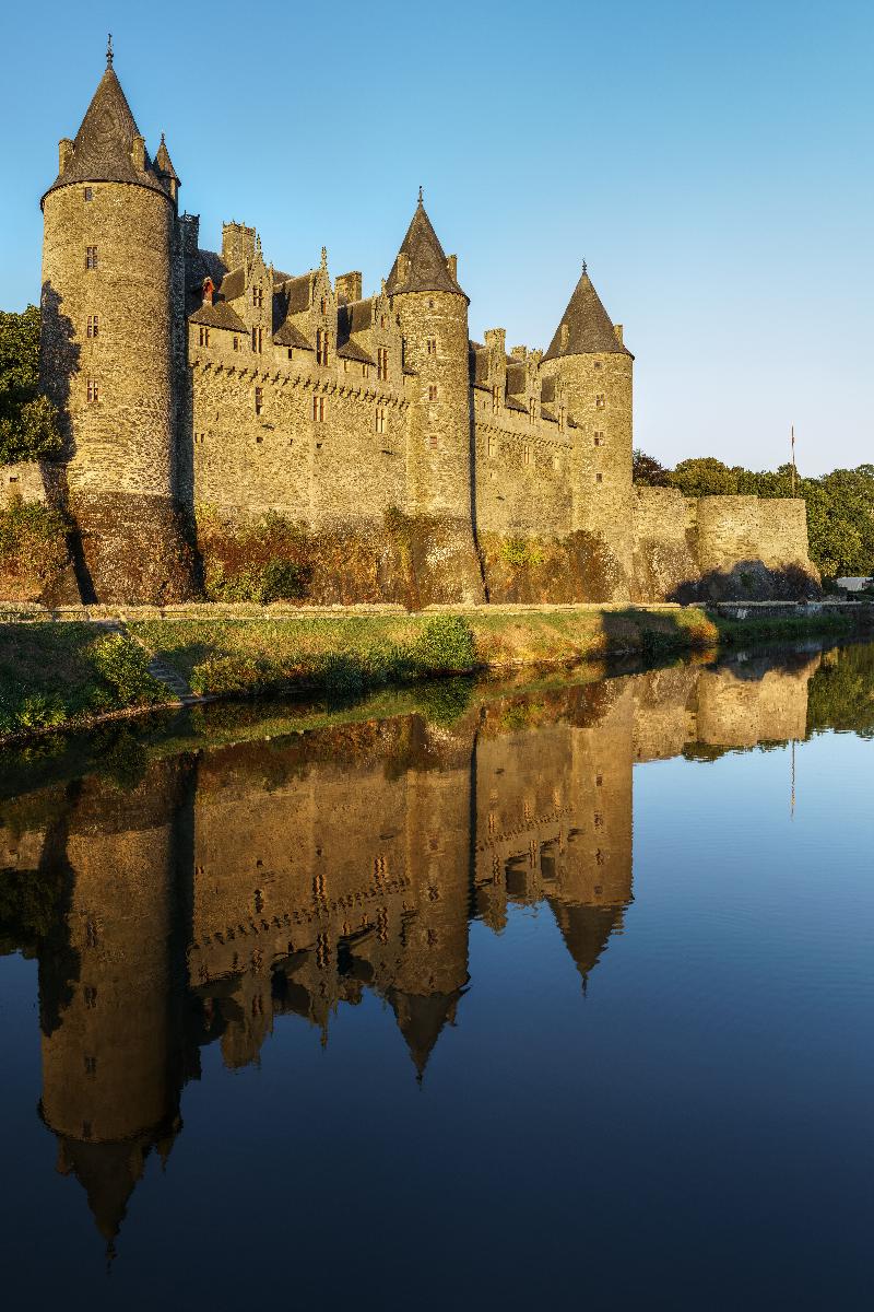Josselin Castle Taken from the bridge across the river Oust in Josselin on a very calm August evening. The château was lit with golden sunlight and reflected in the relatively still water.