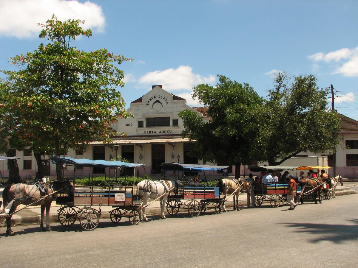 Santa Clara Station Marta Abreu train station from Santa Clara city in Cuba, across the Marty's Park. A line of horse drawn taxi carriages awaits their turn to fill up with travelers.
