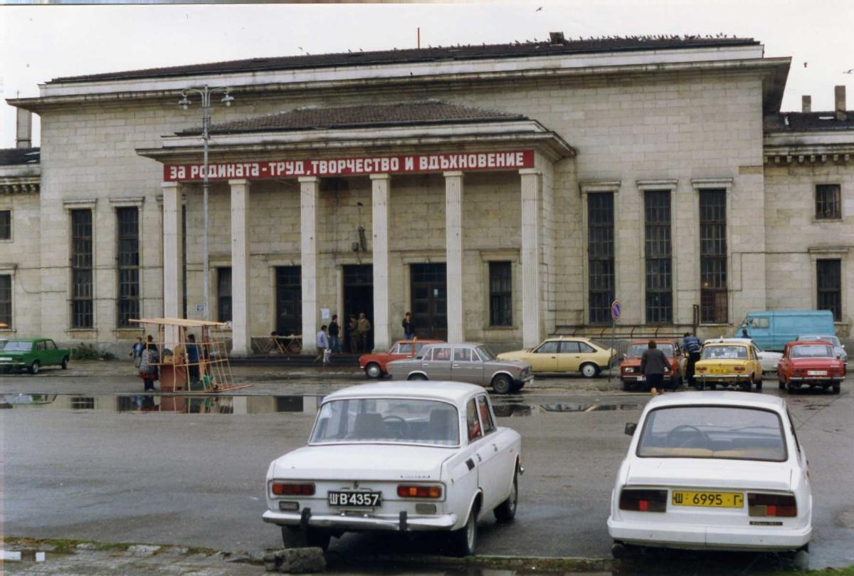 Train station in Shumen, Bulgaria Some rare slogans (see below) adorn the building which is surrounded by a wonderful array of eastern european autos.
The building is the railways station of Shumen and the slogan on it says "For the Fatherland - labor, creativity and inspiration"