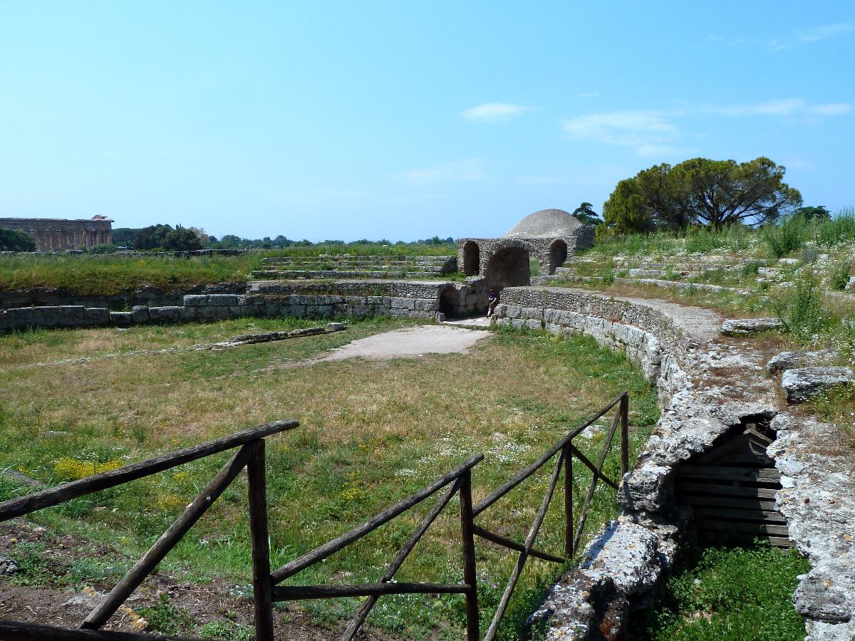Amphitheatre, looking to west entrance, Paestum Temple of Neptune is beyond to the left