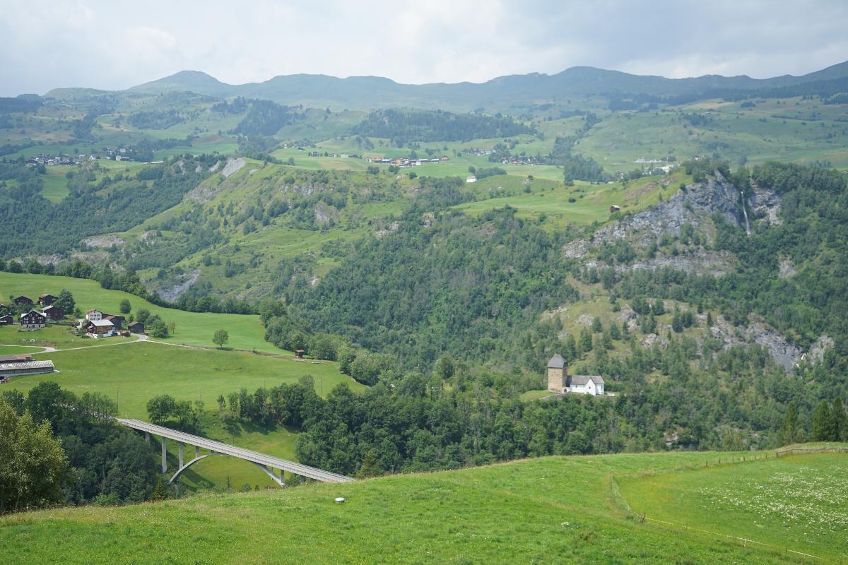 Valserrheinbrücke, Vals Val Lumnezia (Kanton Graubünden) mit der Kirche Sogn Luregn und der Brücke nach Surcasti, darüber Vattiz und Vignogn (links), darüber der Piz Mundaun